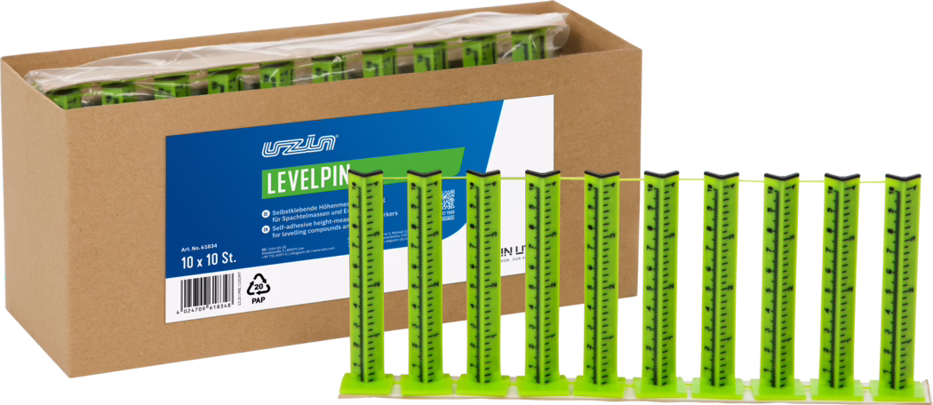 UZIN_Dummy_Levelpin_2026-02 Een kartonnen doos met meerdere felgroene zelfklevende nivelleringspinnen; vooraan staan tien verticale meetstrippen op een basis verbonden met een dun gele draad, op de doos een blauw-wit productlabel met 'LEVELPIN'.